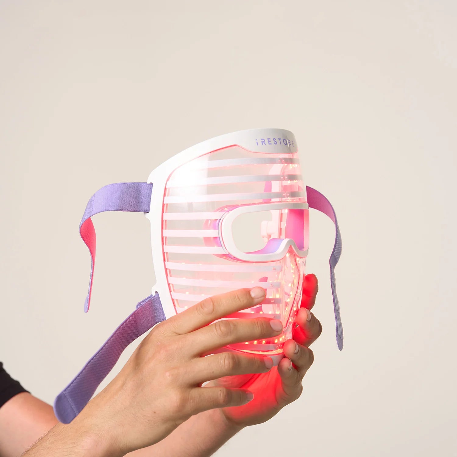 Close up shot of hands holding the LED face mask with red light turned on